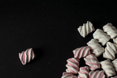 Marshmallow boşaltmak siyah zemin üzerine. Düz yatıyordu veya en iyi görünümü. Arka plan veya doku renkli mini lokum gibiydi.