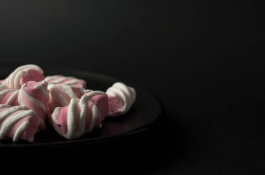 Marshmallow boşaltmak siyah zemin üzerine. Düz yatıyordu veya en iyi görünümü. Arka plan veya doku renkli mini lokum gibiydi.