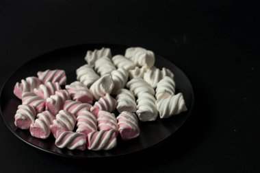 Marshmallow boşaltmak siyah zemin üzerine. Düz yatıyordu veya en iyi görünümü. Arka plan veya doku renkli mini lokum gibiydi.