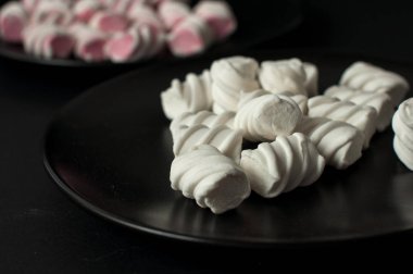 Marshmallow boşaltmak siyah zemin üzerine. Düz yatıyordu veya en iyi görünümü. Arka plan veya doku renkli mini lokum gibiydi.