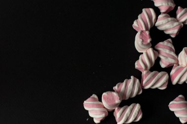 Marshmallow boşaltmak siyah zemin üzerine. Düz yatıyordu veya en iyi görünümü. Arka plan veya doku renkli mini lokum gibiydi.