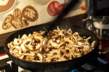 bir tavada soğan ile kavrulmuş mantar