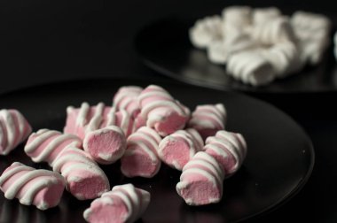 Marshmallow boşaltmak siyah zemin üzerine. Düz yatıyordu veya en iyi görünümü. Arka plan veya doku renkli mini lokum gibiydi.