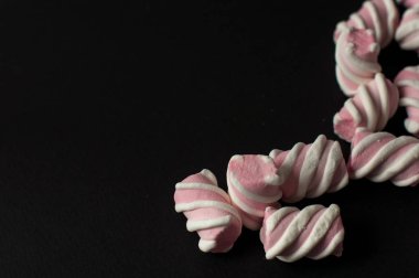 Marshmallow boşaltmak siyah zemin üzerine. Düz yatıyordu veya en iyi görünümü. Arka plan veya doku renkli mini lokum gibiydi.