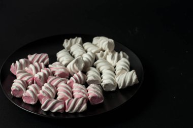 Marshmallow boşaltmak siyah zemin üzerine. Düz yatıyordu veya en iyi görünümü. Arka plan veya doku renkli mini lokum gibiydi.