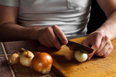 Tahta bir tahtanın üzerinde bıçakla soğan doğramak ve doğramak.