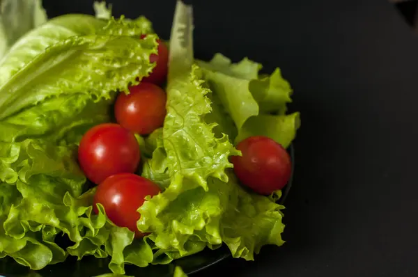 Sağlıklı vejetaryen salata domates ve marul üzerine siyah plaka
