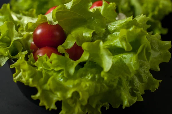 Sağlıklı vejetaryen salata domates ve marul üzerine siyah plaka