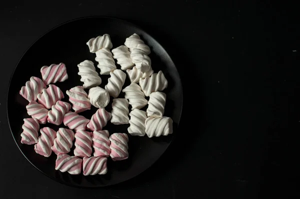 Marshmallows på svart bakgrund med copyspace. Platt lekmanna eller övre vyn. Bakgrund eller konsistens av färgglada mini marshmallows. — Stockfoto