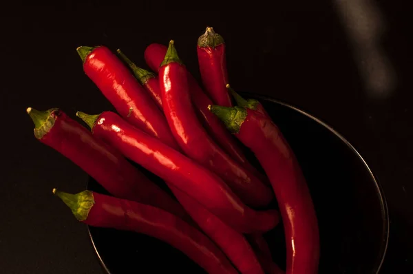 Rode chili pepers op een zwarte achtergrond — Stockfoto