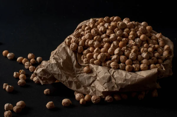 Karanlık yüzey zemin üzerine üzerinde ahşap bir tencerede çiğ nohut taneleri