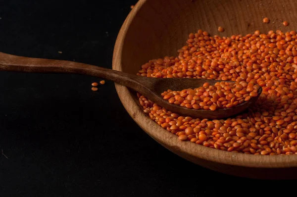 Heap de lentilhas vermelhas em uma tigela de madeira no fundo escuro — Fotografia de Stock