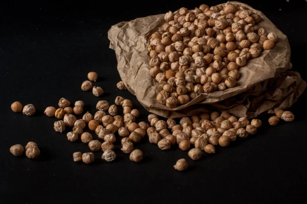 Karanlık yüzey zemin üzerine üzerinde ahşap bir tencerede çiğ nohut taneleri