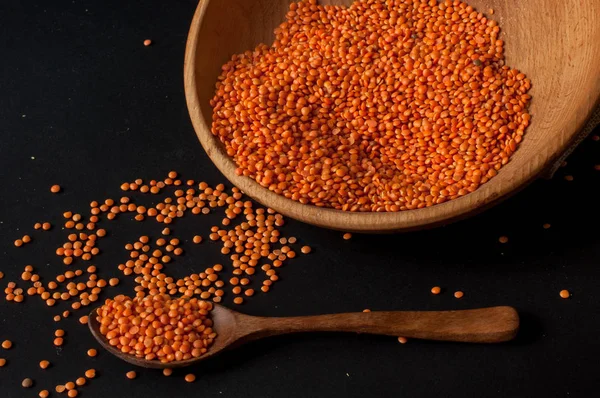 Heap de lentilhas vermelhas em uma tigela de madeira no fundo escuro — Fotografia de Stock