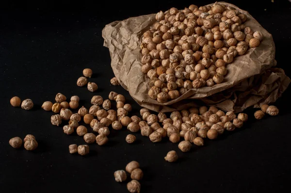 Karanlık yüzey zemin üzerine üzerinde ahşap bir tencerede çiğ nohut taneleri