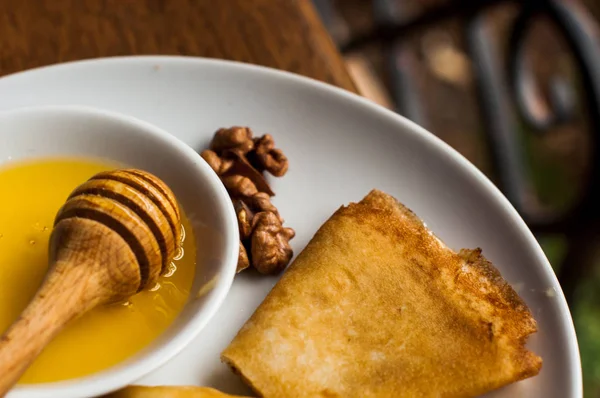 Krep beyaz tabakta bal şurubu ile. geleneksel krep krep hafta veya Shrovetide için. Krep ile kavrulmuş fındık