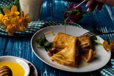 Krep beyaz tabakta bal şurubu ile. geleneksel krep krep hafta veya Shrovetide için. Krep ile kavrulmuş fındık