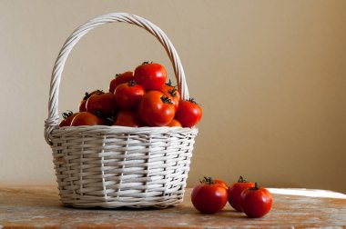 Ahşap masa üzerinde beyaz bir arka plan üzerinde dokuma sepet içinde kırmızı domates