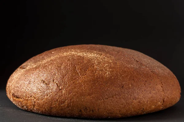 Um rolo de pão close-up em um fundo escuro — Fotografia de Stock