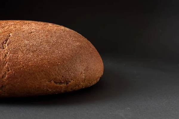 Egy vekni kenyér közelről egy sötét háttér — Stock Fotó
