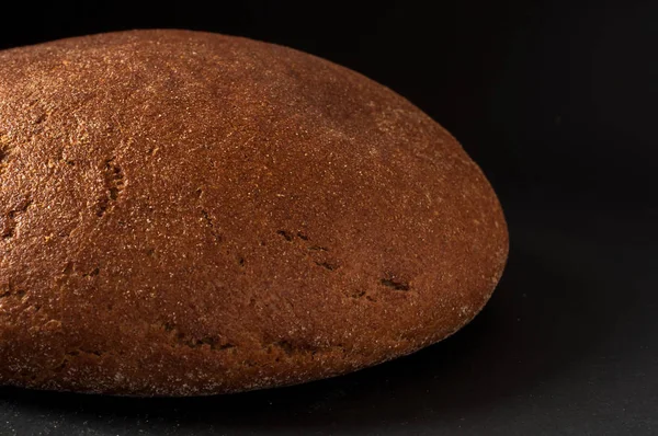 Um rolo de pão close-up em um fundo escuro — Fotografia de Stock