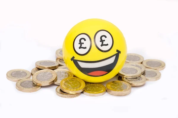 Emoji feliz sentado no topo da pilha de moedas de libra, dinheiro britânico — Fotografia de Stock
