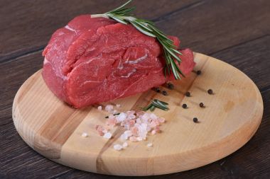 Tuz ve biber ile bir yuvarlak kesme tahtası üzerinde ham taze et