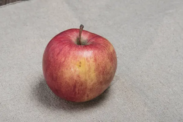Спелое яблоко на мешковине — стоковое фото