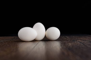 Üç beyaz tavuk yumurtası ahşap bir masa üzerinde