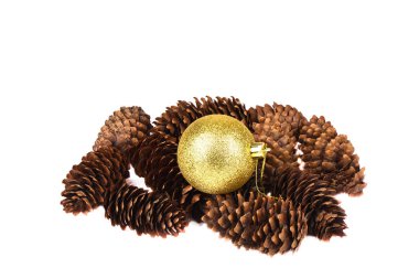 Noel oyuncağı. Beyaz arka planda, Noel ağacı konilerinin üzerinde sarı parlak top..