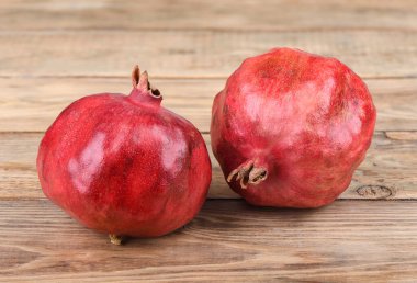 Tahta bir masada iki olgun nar meyvesi..