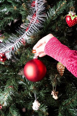 Kız Noel ağacını kırmızı bir topla süslüyor..