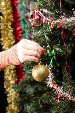 Kız Noel ağacını altın bir topla süslüyor..