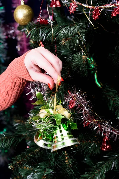 女の子は緑の鐘とクリスマスツリーを飾る. — ストック写真