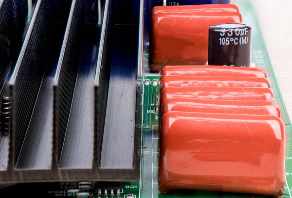 Линия конденсаторов и черный радиатор для охлаждения на электронной плате . — стоковое фото