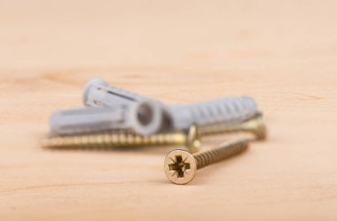 Seçici odaklanma. Tahta arka planda metal vidalar ve plastik kaplamalar. Kapatın. Boşluğu kopyala.