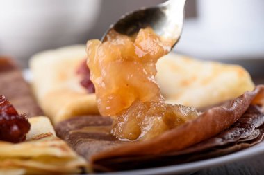 Seçici odaklanma. Krep yerine elmalı reçelli kaşık. Krep sıradandır ve hamura kakao eklenir. Makro atış. Geleneksel Rus kahvaltısı.