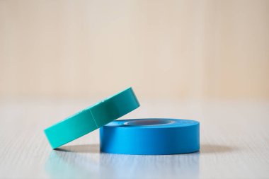 Elektrik kablolarını izole etmek için mavi ve yeşil izolasyon bantları. Tahta masadaki bantları izole etmek. Kapat..