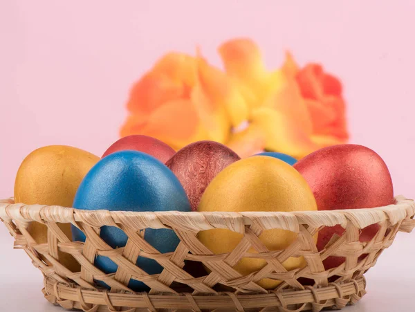 Выборочный фокус. Корзина с разноцветными пасхальными яйцами и размытыми цветами на заднем плане . — стоковое фото