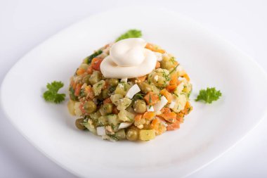 Haşlanmış havuç, patates, yumurta ve konserve bezelye içeren diyet vitamin salatası. Salata mayonezle süslenmiş. Beyaz tabakta salata. Sağlıklı beslenme
