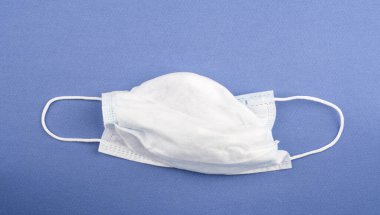 Mavi arka planda fotokopi alanı olan tek kullanımlık tıbbi maske. Enfeksiyona karşı korumak için tıbbi maske.