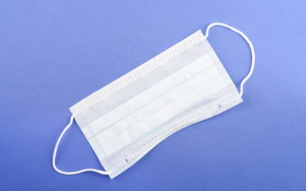 Disposable medical mask on a blue background with copy space. Medical mask to protect against infection.