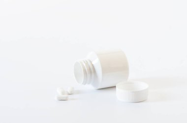 Beyaz arka planda beyaz haplar ve plastik şişe. Sağlık konsepti. Boşluğu kopyala.
