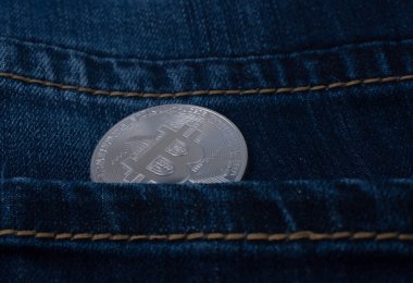 Bitcoin altın sikke mavi kot pantolon cebinde.