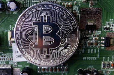 Gümüş Hediyelik eşya sikke Bitcoin bilgisayar devre kartı arka plan üzerinde.