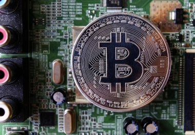 Gümüş Hediyelik eşya sikke Bitcoin bilgisayar devre kartı arka plan üzerinde.