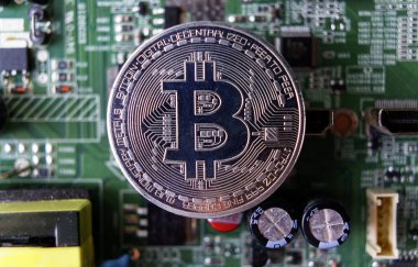 Gümüş Hediyelik eşya sikke Bitcoin bilgisayar devre kartı arka plan üzerinde.