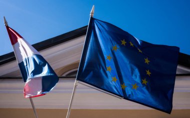 Avrupa 'nın güneşli havasında bina üzerinde Hollanda ve Avrupa Birliği bayrakları