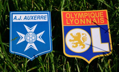6 Eylül 2019, Paris, Fransa. Fransız futbol kulüpleri Olympique Lyonnais ve Auxerre 'in amblemleri çimlerin yeşil çimlerinde.