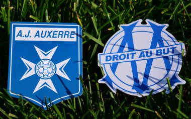 6 Eylül 2019, Paris, Fransa. Fransız futbol kulüpleri Olympique de Marsilya ve Auxerre 'in amblemleri çimlerin yeşil çimlerinde..